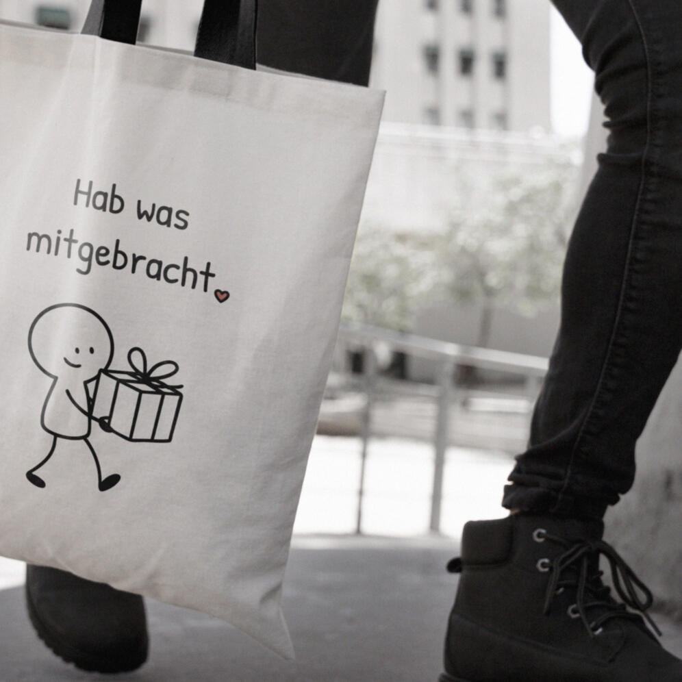 Baumwollbeutel mit minimalistischer Figur, die ein Geschenk trägt und dem Spruch "Hab was mitgebracht.".