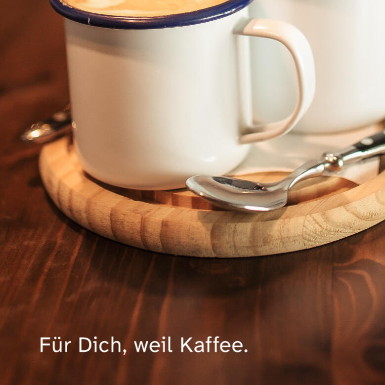 Zwei schlichte Kaffeetassen stehen ruhig nebeneinander in warmer Umgebung. Dezenter Text im Bild: „Für dich, weil Kaffee.“ Stimmung: still, freundlich, ohne Produktfokus.